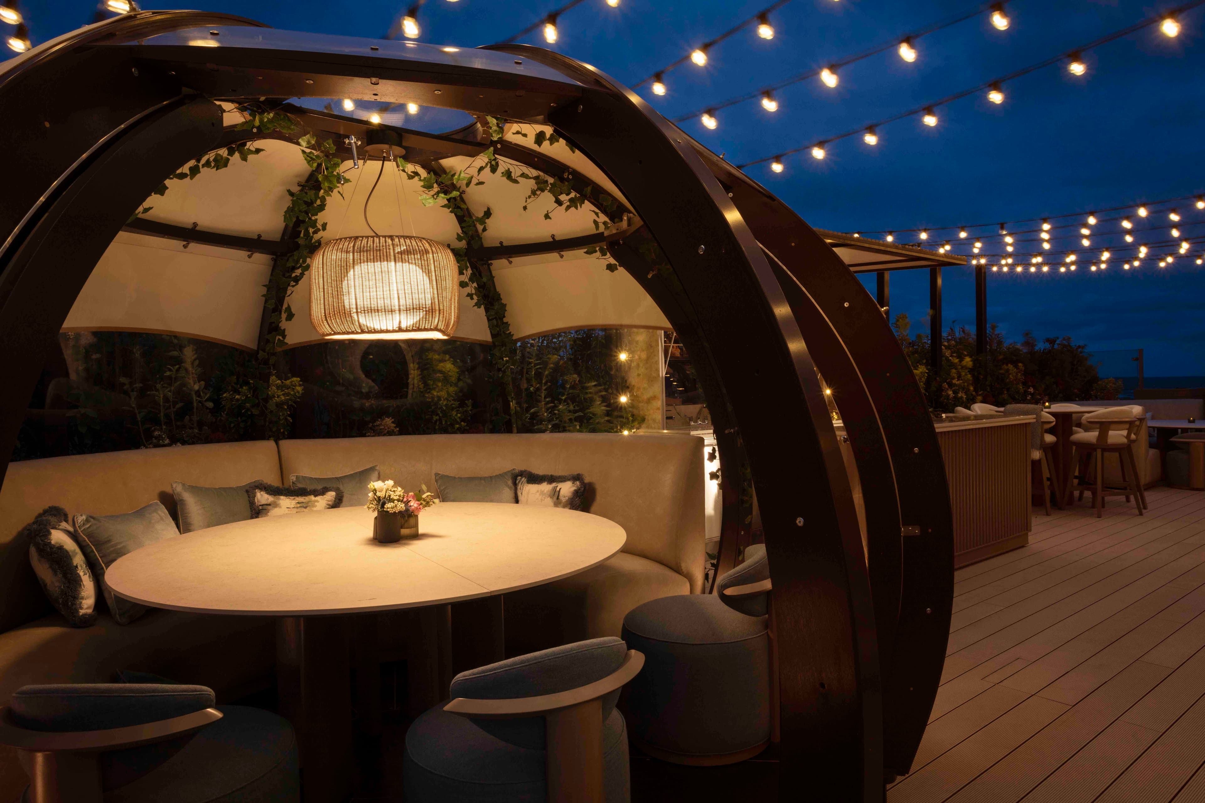 Cosy pods illuminated by fairy lights at dusk on the West Deck, The Old Course Hotel, perfect for evening gatherings